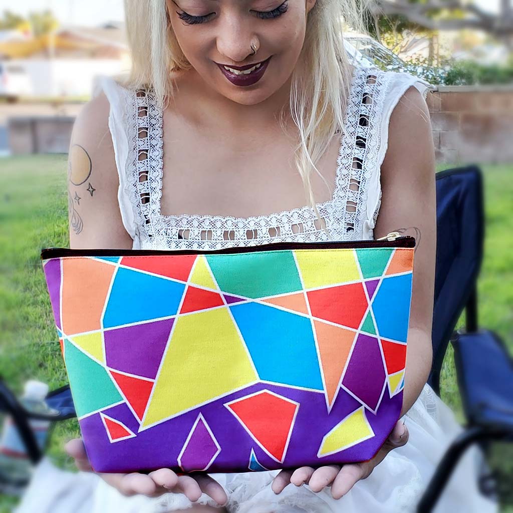 A beautiful woman holds a large zippered pouch in the multicolor Prism design by My Friend Ren.