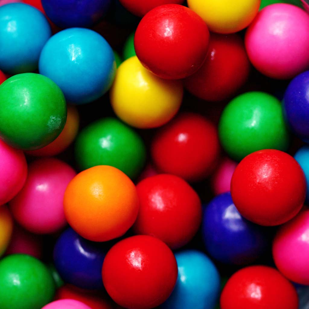 Closeup on a mass of colourful and shiny gumballs.