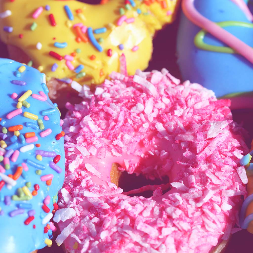 Closeup photo of colourful doughnuts with a variety of rainbow-coloured sprinkles