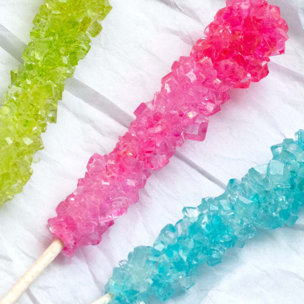 Closeup of rock candy sticks in three different colours: lime green; pink; and blue.