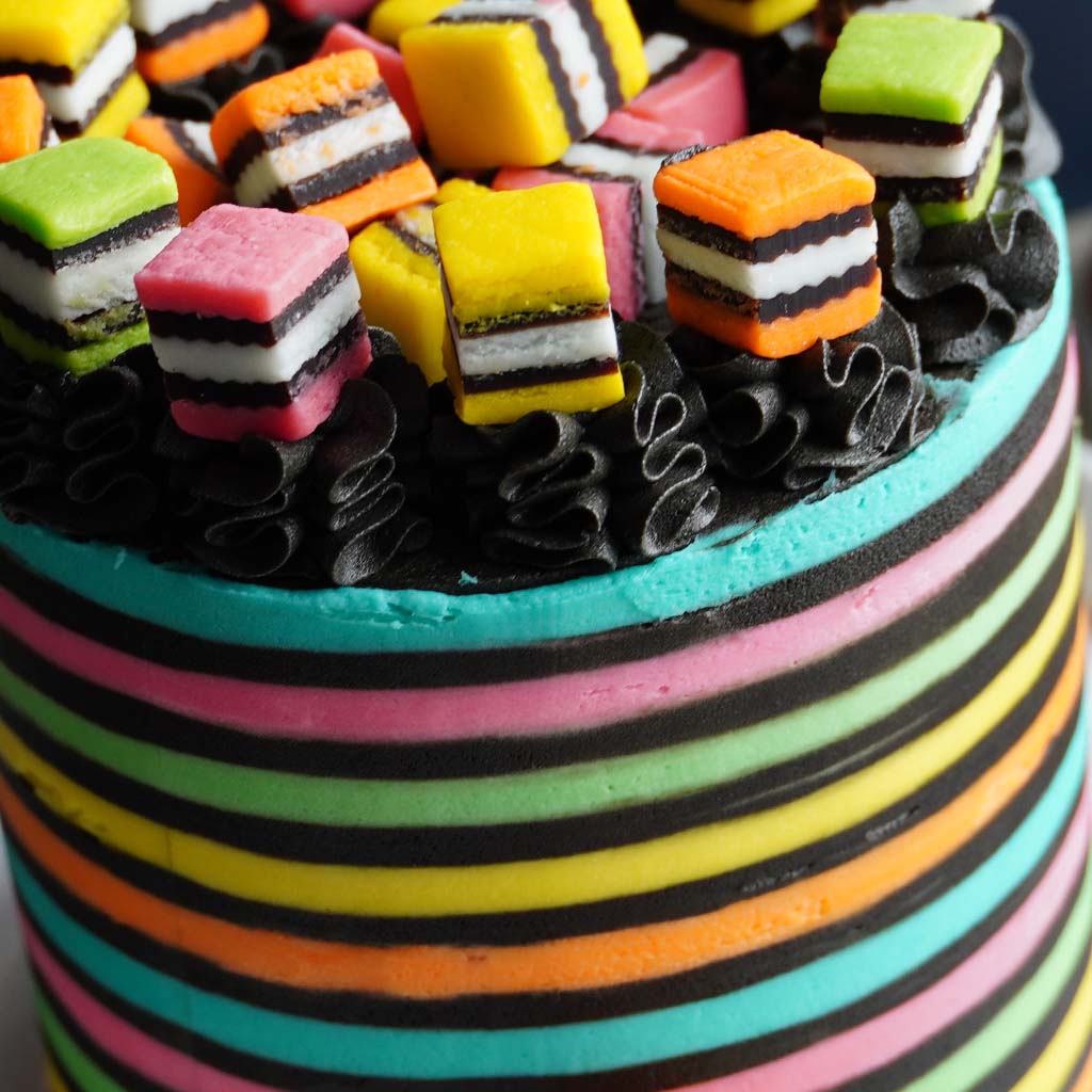 Closeup of a rainbow-striped cake with striped candy on top